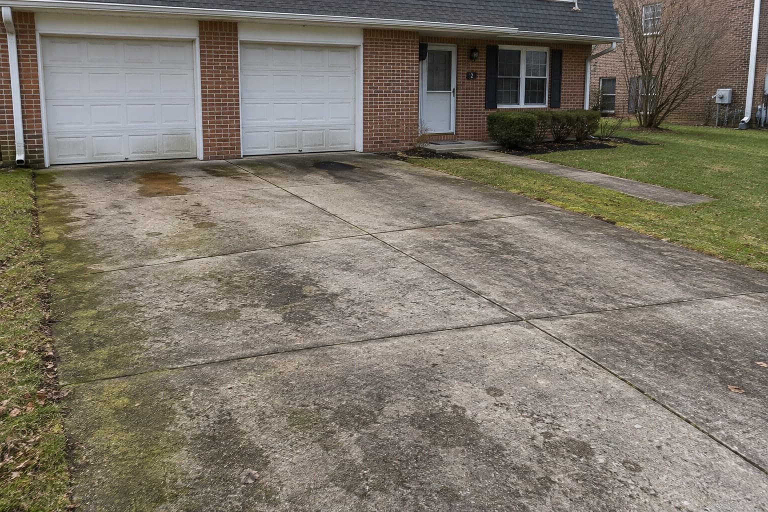 Stained concrete driveway and entry walk at a duplex, before pressure washing